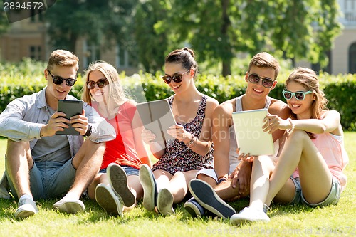 Image of smiling friends with tablet pc computers in park