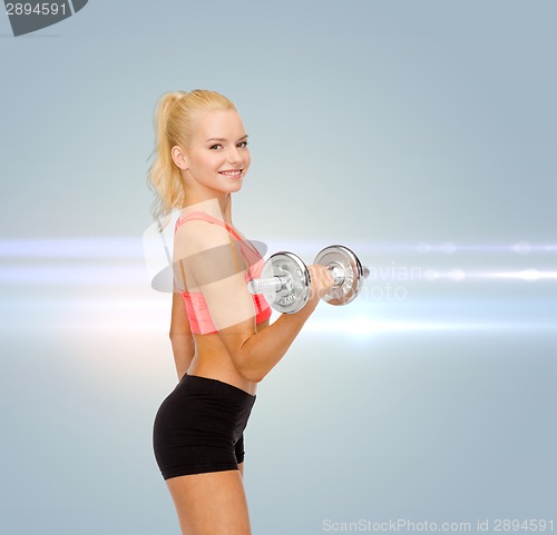 Image of young sporty woman with heavy steel dumbbell