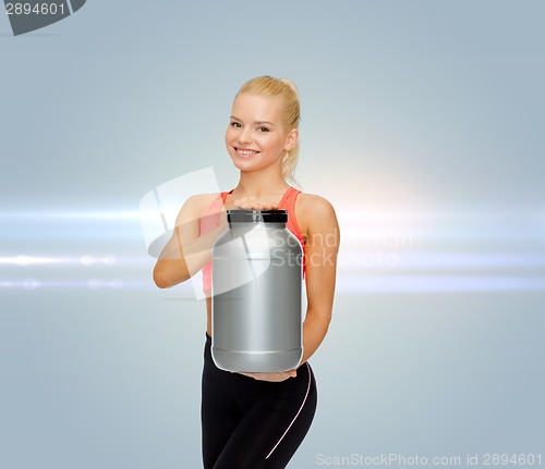 Image of smiling sporty woman with jar of protein