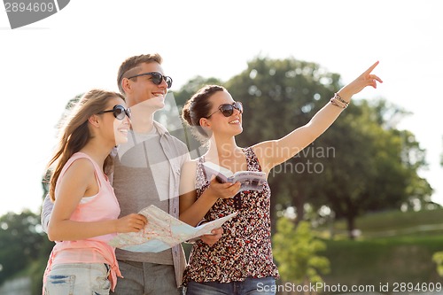 Image of smiling friends with map and city guide outdoors