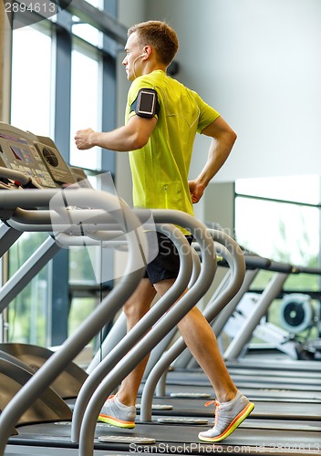 Image of man with smartphone exercising on treadmill in gym