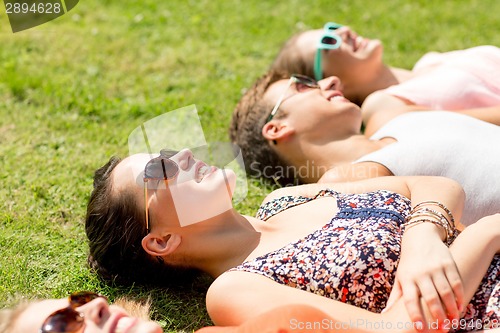 Image of group of smiling friends lying on grass outdoors