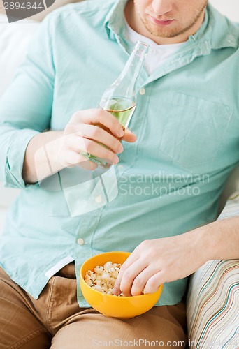 Image of close up of man with popcorn and beer at home