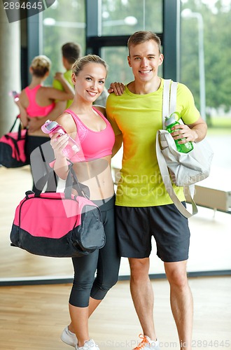 Image of smiling couple with water bottles in gym