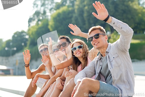 Image of group of smiling friends sitting on city street