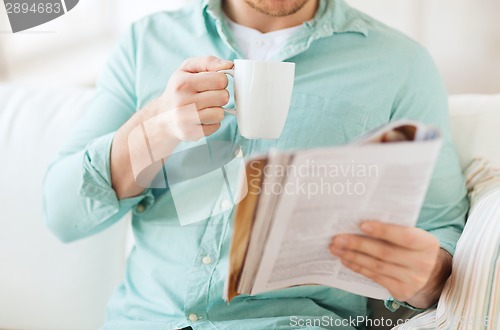 Image of close up of man with magazine drinking from cup