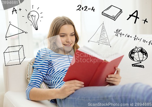 Image of smiling teenage girl reading book on couch