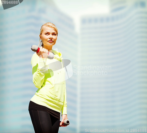 Image of sporty woman with light dumbbells outdoors