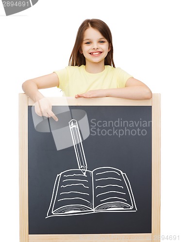 Image of smiling little girl pointing finger to blackboard