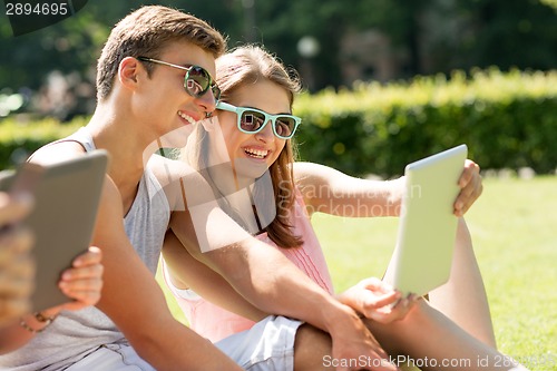 Image of smiling friends with tablet pc computers in park