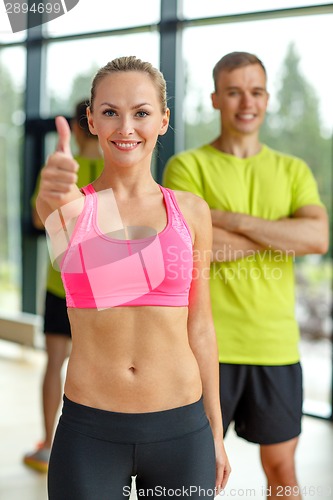 Image of smiling man and woman showing thumbs up in gym