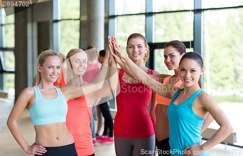 Image of group of women making high five gesture in gym