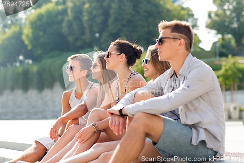Image of group of smiling friends sitting on city square
