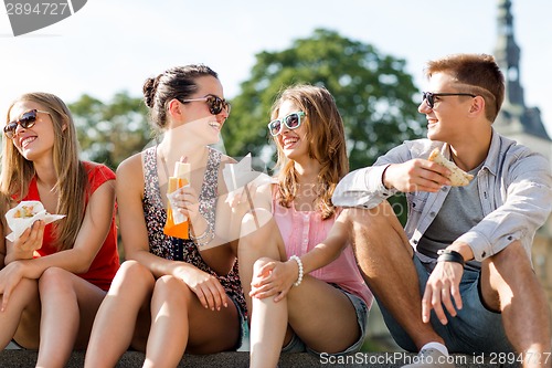 Image of group of smiling friends sitting on city square