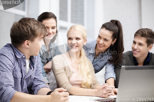 Image of group of smiling students with laptop at school