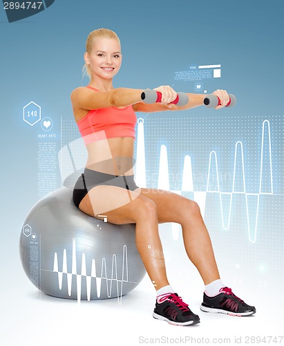 Image of woman with dumbbells sitting on fitness ball