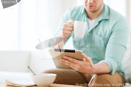 Image of close up of man with tablet pc having breakfast