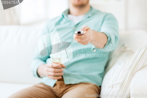 Image of man with beer and remote control at home