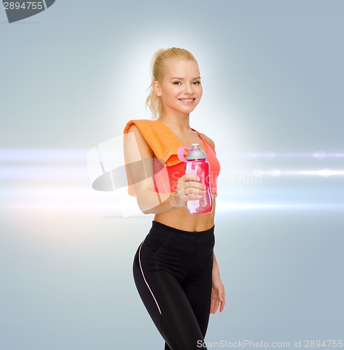 Image of smiling sporty woman with water bottle and towel