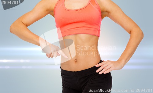 Image of close up of woman pointing finger at her six pack