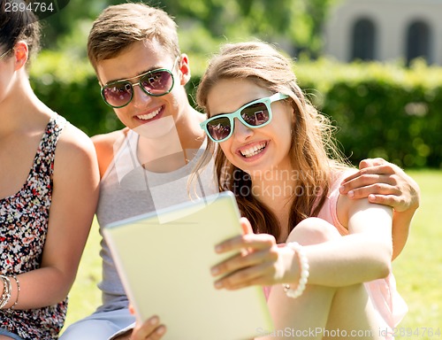 Image of smiling friends with tablet pc computers in park