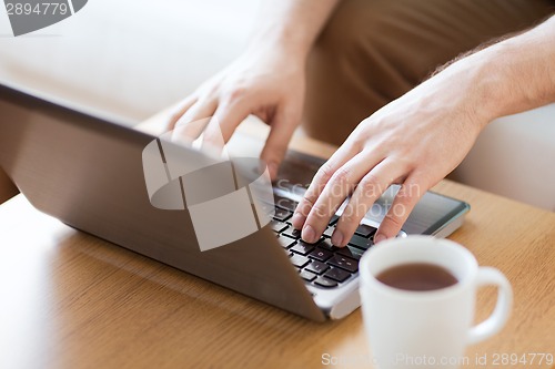 Image of close up of man with laptop and cup at home