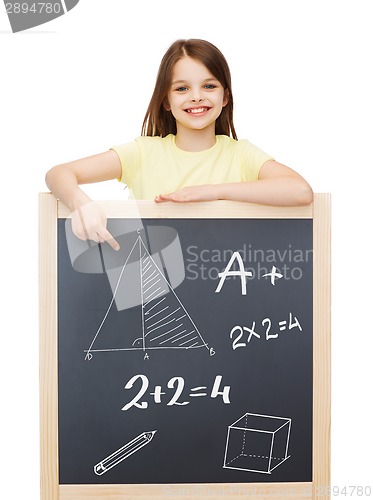 Image of smiling little girl pointing finger to blackboard