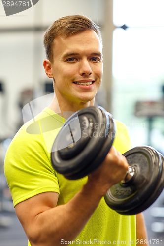 Image of smiling man with dumbbell in gym