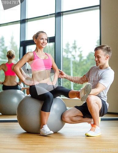 Image of smiling man and woman with exercise ball in gym