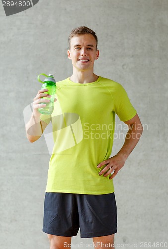 Image of smiling man with bottle of water in gym