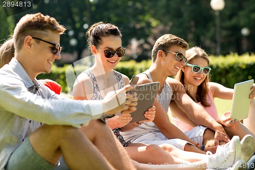 Image of smiling friends with tablet pc computers in park