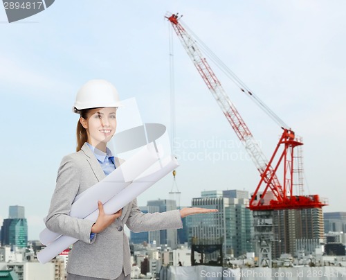 Image of smiling architect in helmet with blueprint
