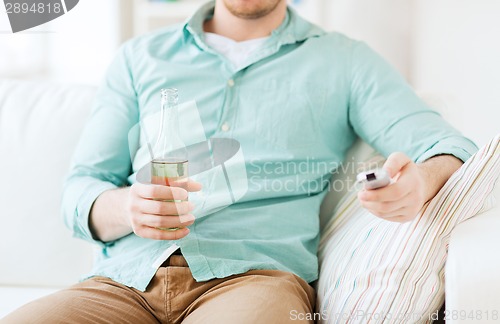 Image of man with beer and remote control at home