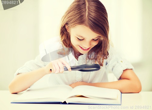 Image of girl reading book with magnifier at school