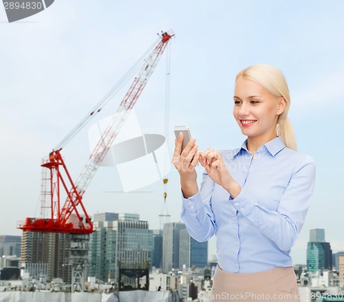 Image of young smiling businesswoman with smartphone