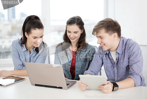 Image of three smiling students with laptop and tablet pc