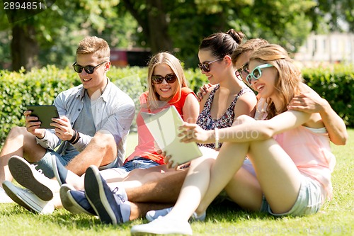 Image of smiling friends with tablet pc computers in park