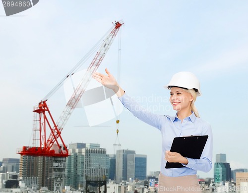 Image of smiling businesswoman in helmet with clipboard