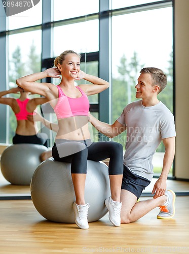 Image of smiling man and woman with exercise ball in gym