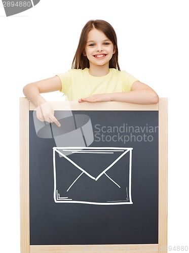 Image of smiling little girl pointing finger to blackboard