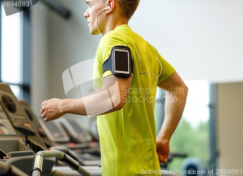 Image of man with smartphone exercising on treadmill in gym
