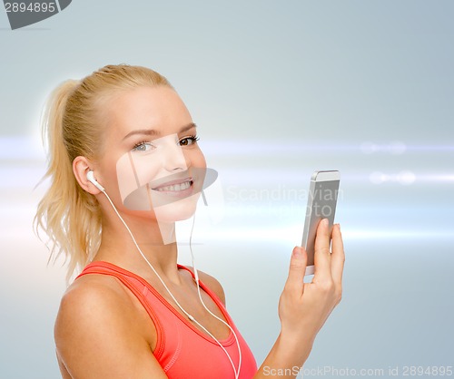 Image of smiling sporty woman with smartphone and earphones