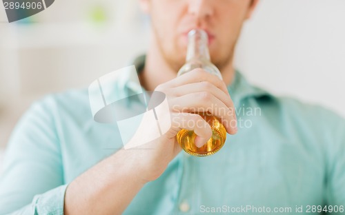 Image of close up of man drinking beer at home