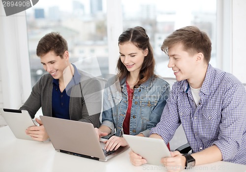Image of three smiling students with laptop and tablet pc