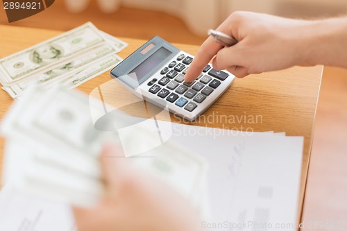 Image of close up of man counting money and making notes