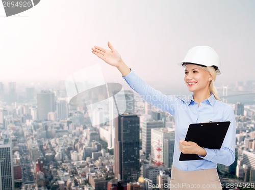 Image of smiling businesswoman in helmet with clipboard