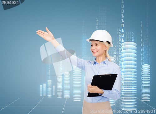 Image of smiling businesswoman in helmet with clipboard