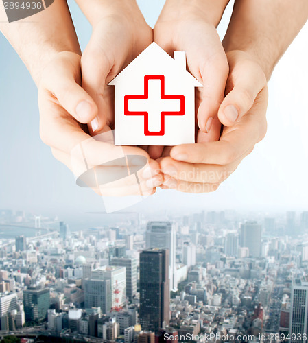 Image of hands holding paper house with red cross