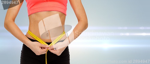 Image of close up of female hands measuring waist