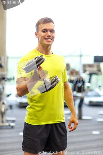Image of smiling man with dumbbell in gym
